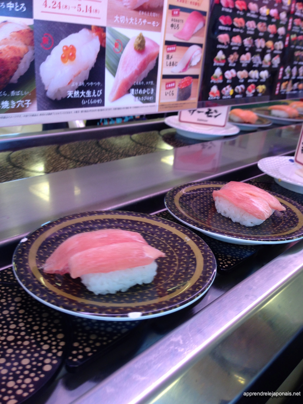Sushis au thon sur des assiettes posées sur un tapis roulant