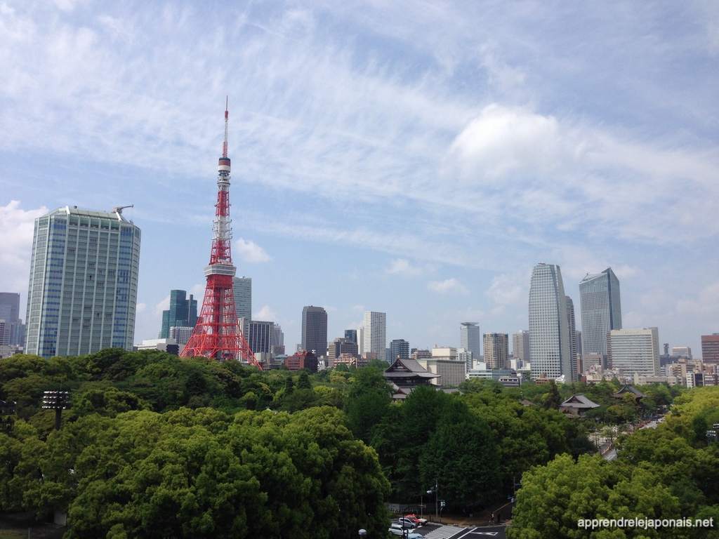 Tour de Tokyo rouge et blanche au-dessus des arbres et des immeubles