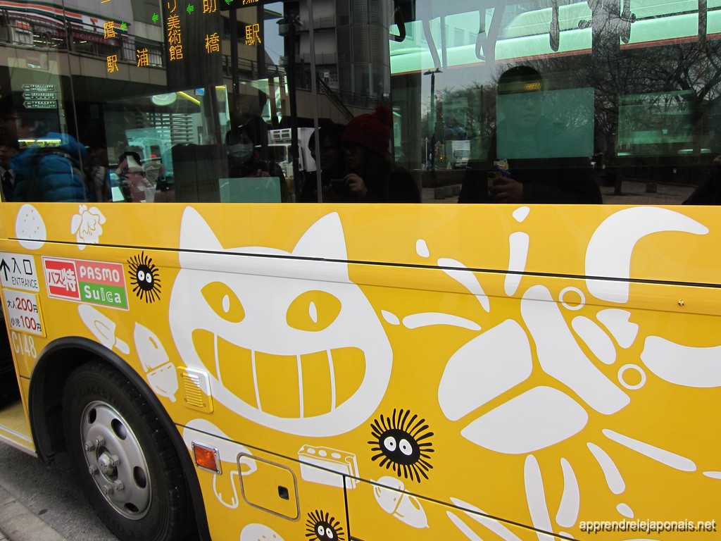 Bus jaune du musée Ghibli décoré d'un chat souriant et de noiraudes