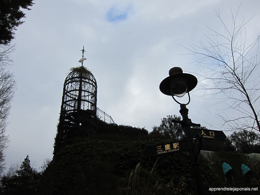 Tour en fer couverte de lierre du musée Ghibli avec un panneau vers la gare de Mitaka