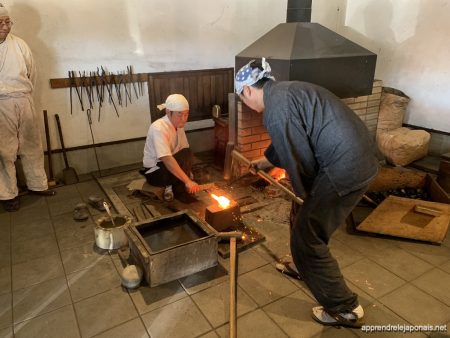 Forgeron frappant du métal chauffé à blanc dans une forge, avec les étincelles