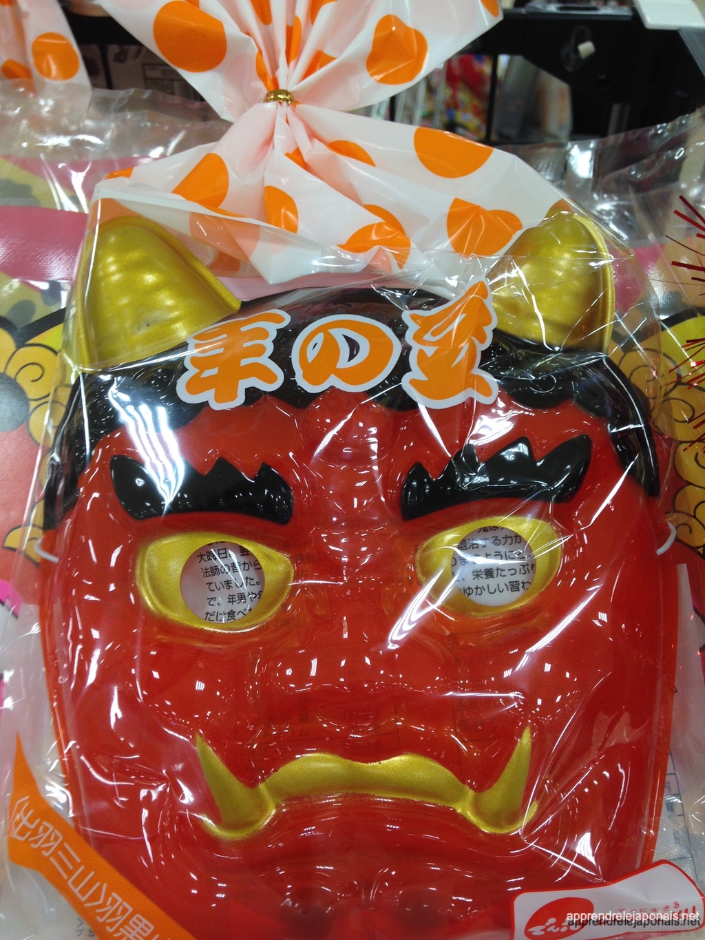Masque d'oni rouge à cornes dorées emballé dans du plastique pour Setsubun