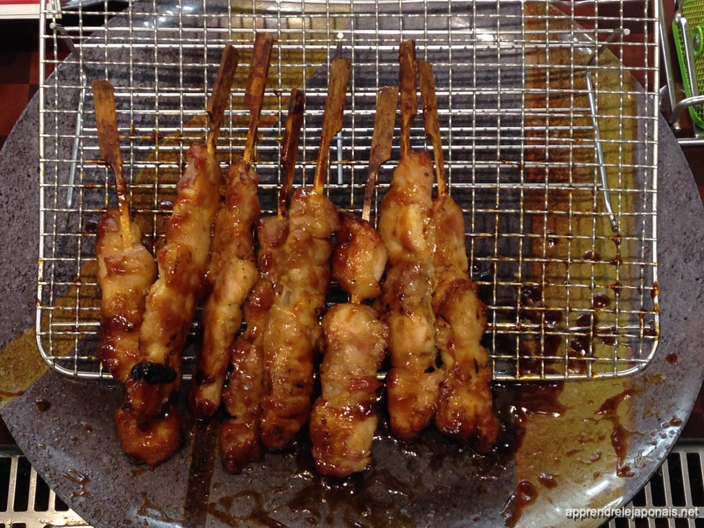 Brochettes de yakitori laquées de sauce posées sur une grille