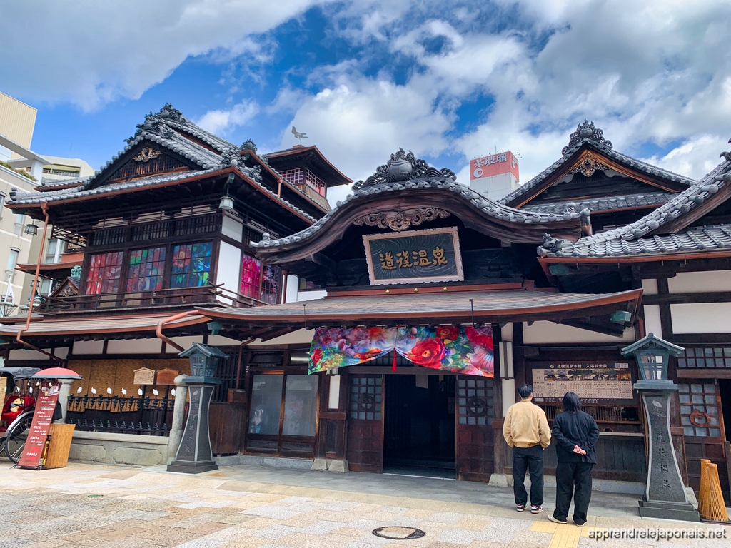 La façade en bois de Dōgo Onsen (道後温泉) à Matsuyama, sous un grand ciel bleu