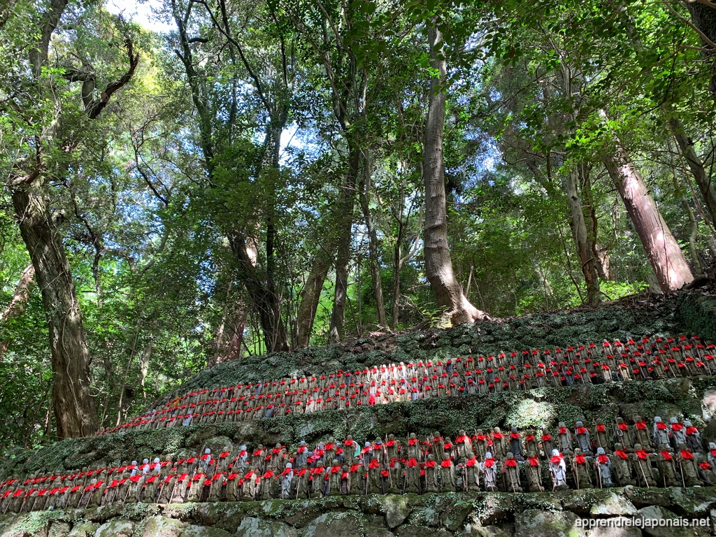 Rangées de statues de Jizō aux bonnets rouges dans la forêt à Himeji
